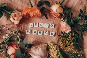 scrabble tiles on pink surface near flowers